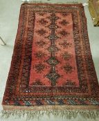 A Turkamen rug, the central panel set with repeating medallions on a red ground,