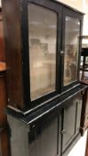 A Victorian black painted bookcase display cabinet with glazed two door upper section over two