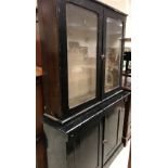 A Victorian black painted bookcase display cabinet with glazed two door upper section over two