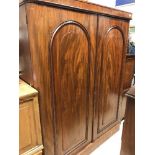 A Victorian mahogany two door wardrobe with arched panelled doors enclosing drawers and hanging