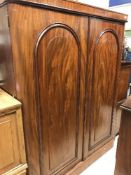 A Victorian mahogany two door wardrobe with arched panelled doors enclosing drawers and hanging