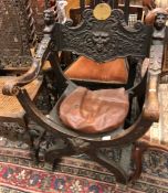 A 19th Century walnut X framed elbow chair with Bacchus mask and grape and vine decorated back rail,