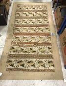 A needlework rug of striped pattern with stylised oak leaves and acorns, on a beige ground, approx.