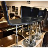 A set of four modern black leather covered adjustable bar stools