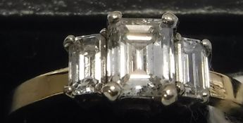 A 14 carat gold diamond set ring, the central emerald cut diamond flanked by two further diamonds,