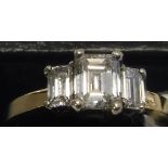 A 14 carat gold diamond set ring, the central emerald cut diamond flanked by two further diamonds,