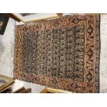 A Kashan rug, the central panel set with repeating hook motifs on a dark ground,