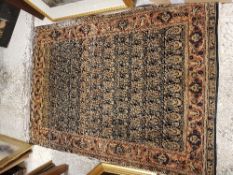 A Kashan rug, the central panel set with repeating hook motifs on a dark ground,