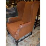An upholstered wing back chair in the Flemish taste raised on scroll supports to bun feet Size