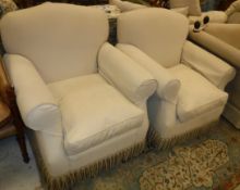 A pair of modern upholstered scroll arm chairs in pale beige with tassled bases by Wright Interiors