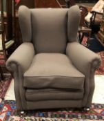 A circa 1900 upholstered wing back scroll armchair on turned feet to castors Size approx 77cm long