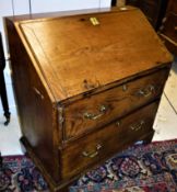 An 18th Century elm bureau the sloping fall enclosing a basic fitted interior over two drawers with