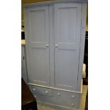 A white painted pine wardrobe with moulded cornice over two cupboard doors enclosing a shelf and