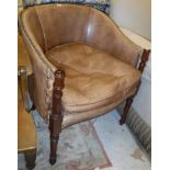 A brown leather yoke back and brass studded elbow chair on turned and ringed mahogany supports