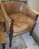 A brown leather yoke back and brass studded elbow chair on turned and ringed mahogany supports