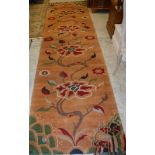 A modern Oriental style runner, the peach ground with multi coloured floral sprays,