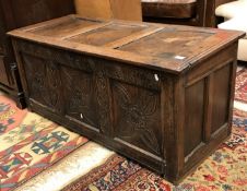 A circa 1700 oak coffer the plain three panel top over a foliate lunette carved frieze and foliate