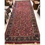 A Sarouk rug with all over scrolling floral and foliate decoration on a plum ground within a blue