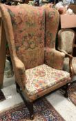 A 19th Century American upholstered wing back scroll arm chair on square supports united by