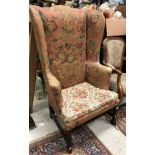 A 19th Century American upholstered wing back scroll arm chair on square supports united by