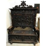 A carved painted and gilded walnut settle in the 17th Century Spanish taste the back with shield