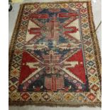 A Shirvan rug with a repeating medallion decoration on a red ground within a scrolling foliate