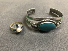 A yellow metal stone and pearl set dress ring together with a silver bangle with turquoise stone