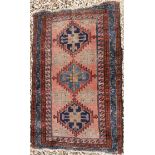 A Caucasian rug with lozenge medallions on a floral motif decorated red ground,