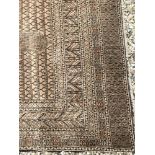 A Bokhara rug with central repeating rectangular medallions on a faded red ground within a