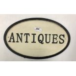 A painted metal oval "Antiques" sign