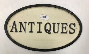 A painted metal oval "Antiques" sign