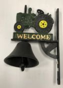 A painted cast metal sign inscribed "Welcome" and decorated with a tractor and bell