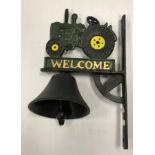 A painted cast metal sign inscribed "Welcome" and decorated with a tractor and bell