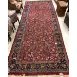 A Sarouk rug with all over scrolling floral and foliate decoration on a plum ground within a blue