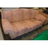 A modern terracotta / gold upholstered floral decorated sofa on turned legs to castors in the