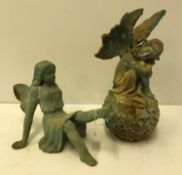 A verdigris patinated figure of an angel sat upon a flower ball and another seated with dove upon