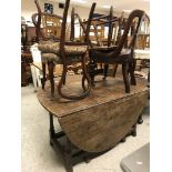 An oak drop-leaf table together with four various chairs