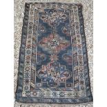A Caucasian rug with repeating medallions on a dark blue ground, within a barber pole,