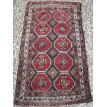 A Caucasian rug with repeating elephant foot style and lozenge medallion decoration on a dark brown