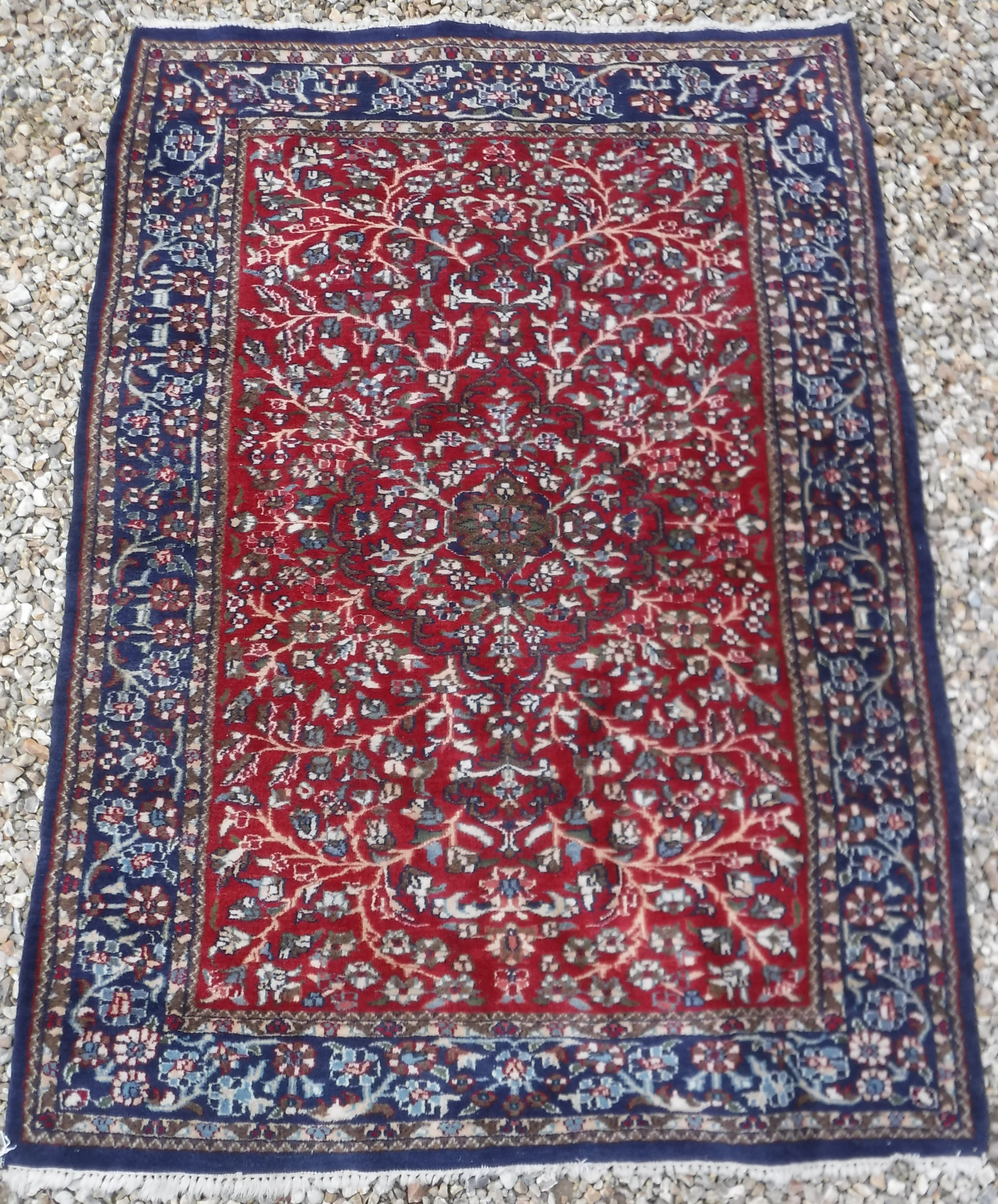 A Persian rug with centre medallion on a floral and foliate decorated red ground,