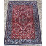 A Persian rug with centre medallion on a floral and foliate decorated red ground,