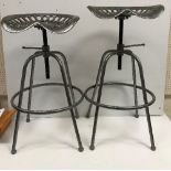 A pair of silver painted iron tractor seat stools