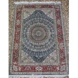 A Persian silk rug with circular centre medallion on a blue ground,