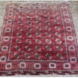 A Bokhara carpet with all over elephant foot medallion decoration on a red ground,