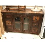 A modern teak sideboard with two glazed doors flanked by two banks of three drawers,