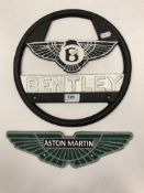A painted cast metal "Bentley" steering wheel type sign and an "Aston Martin" sign