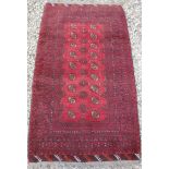 A Turkamen rug with repeating elephant foot medallions on a red ground,