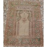 A Turkish silk prayer rug with architectural and lantern centre field on a green ground,