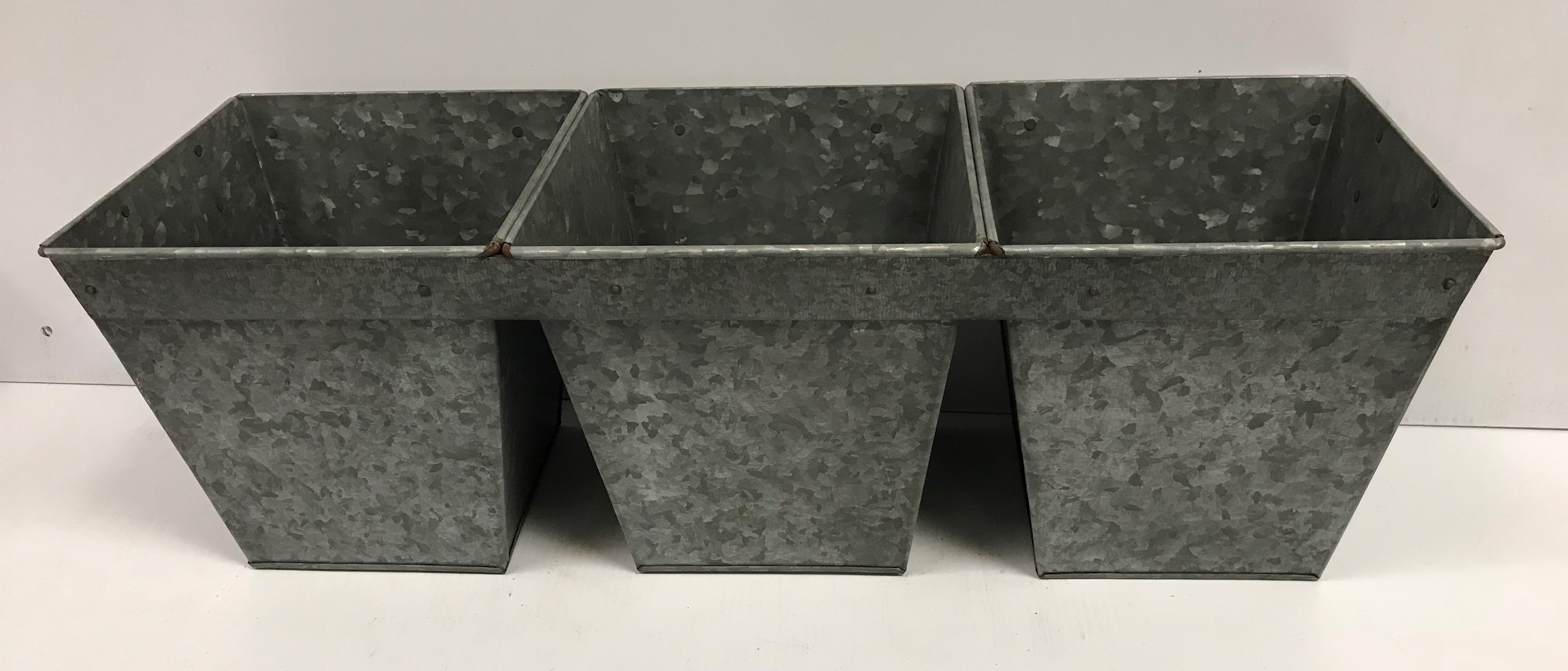 A set of three interconnected galvanised planters