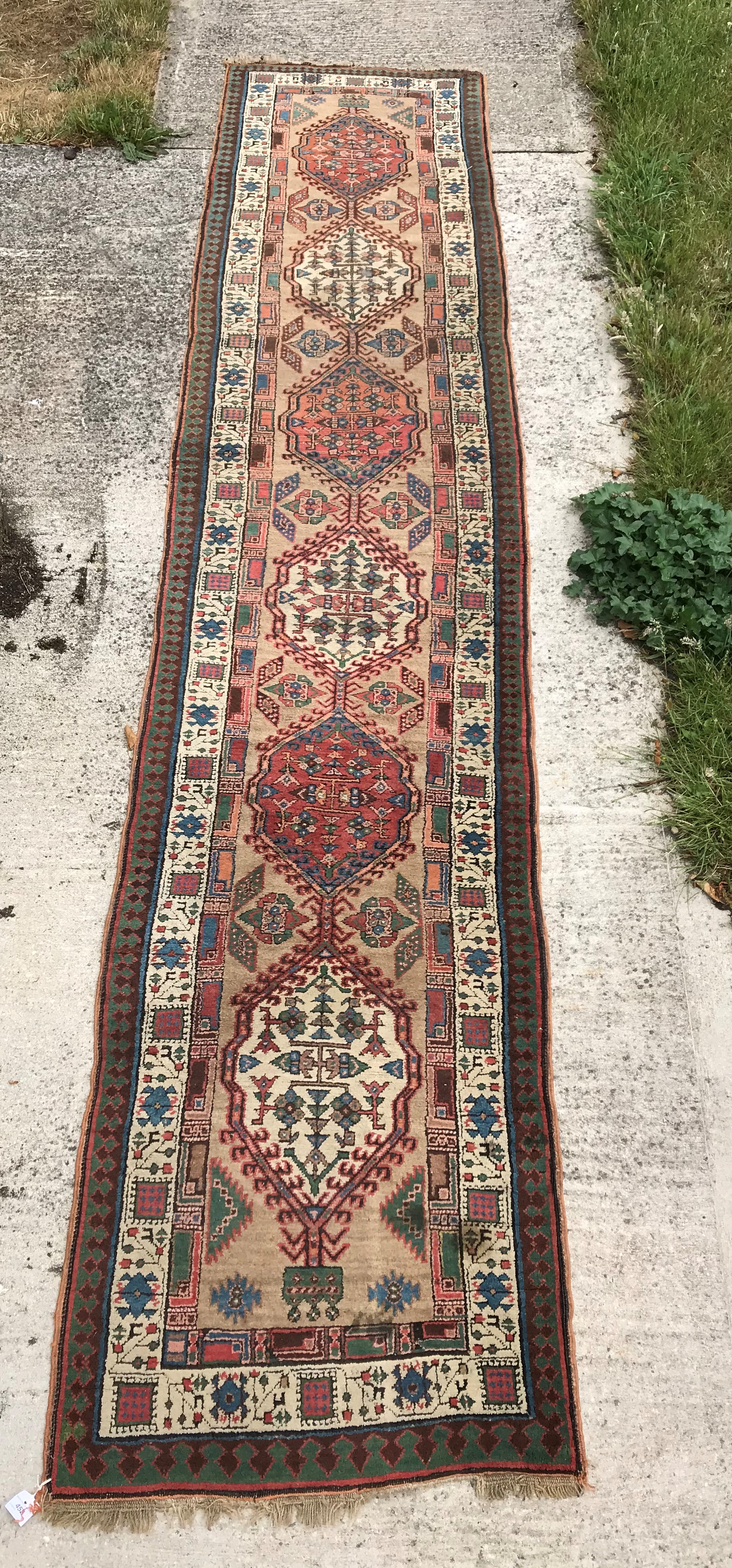 A Caucasian runner with repeating medallions on a fawn ground,